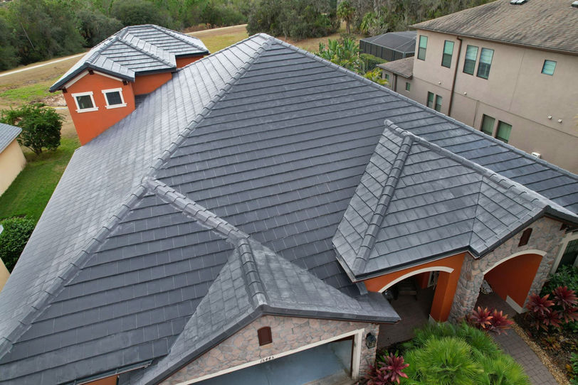 Aerial view of a Mediterranean-style residence with complex multi-plane hip roof covered in solar roof tiles