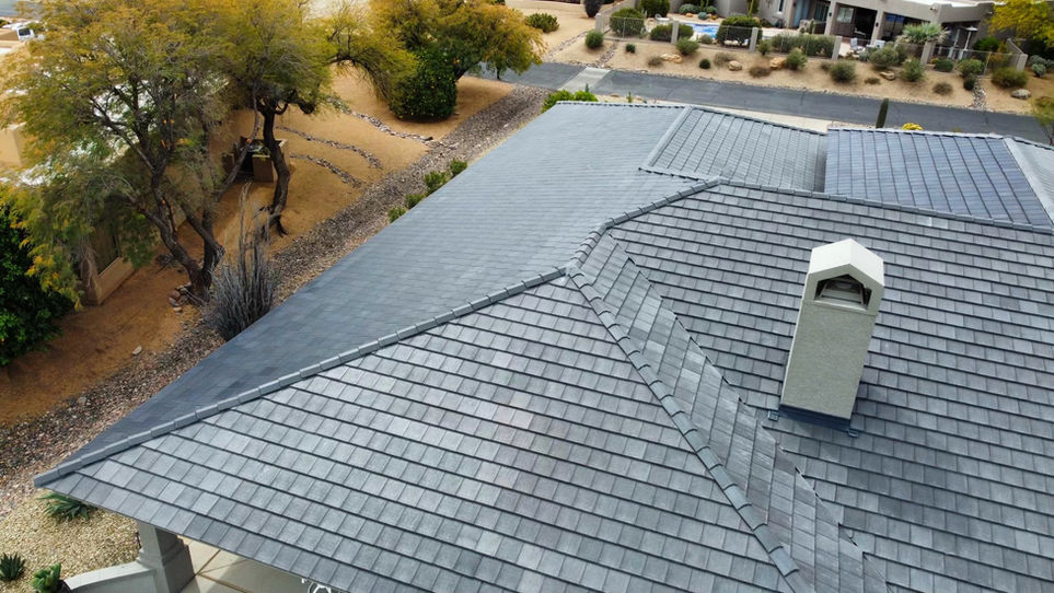 Aerial view of a residential property with full solar roof tile coverage and chimney detail