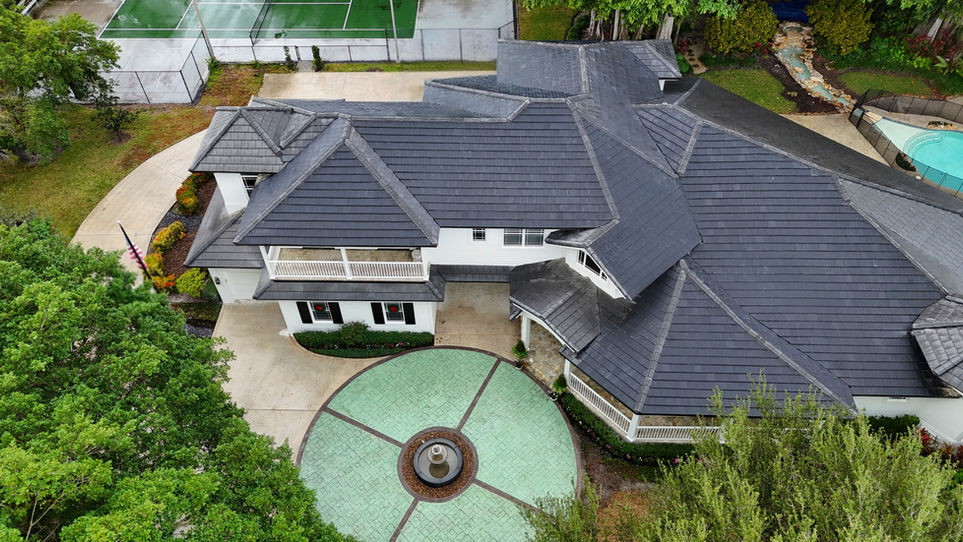 Aerial view of a premium estate property with complete solar roof tile coverage, pool and tennis court visible