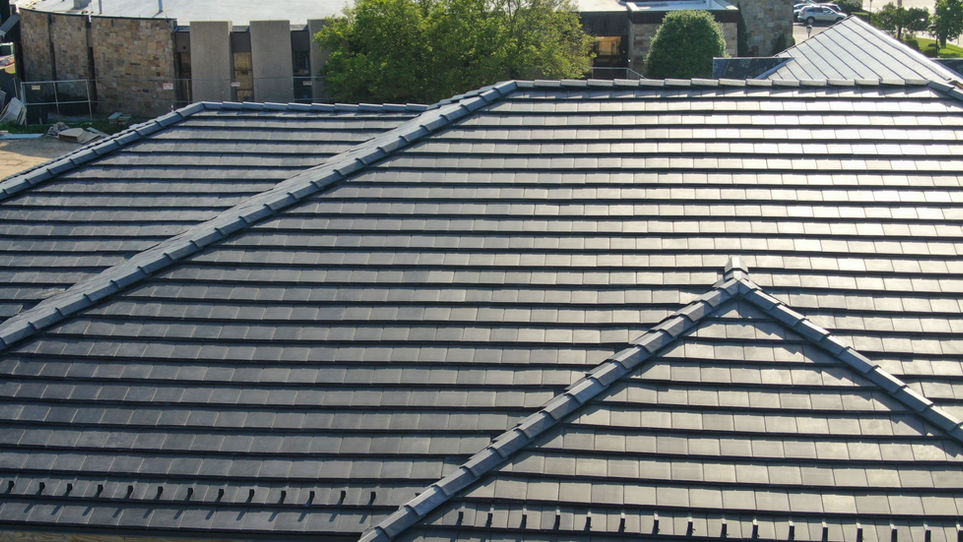 Aerial view of a stone and brick building with a clean solar roof tile installation